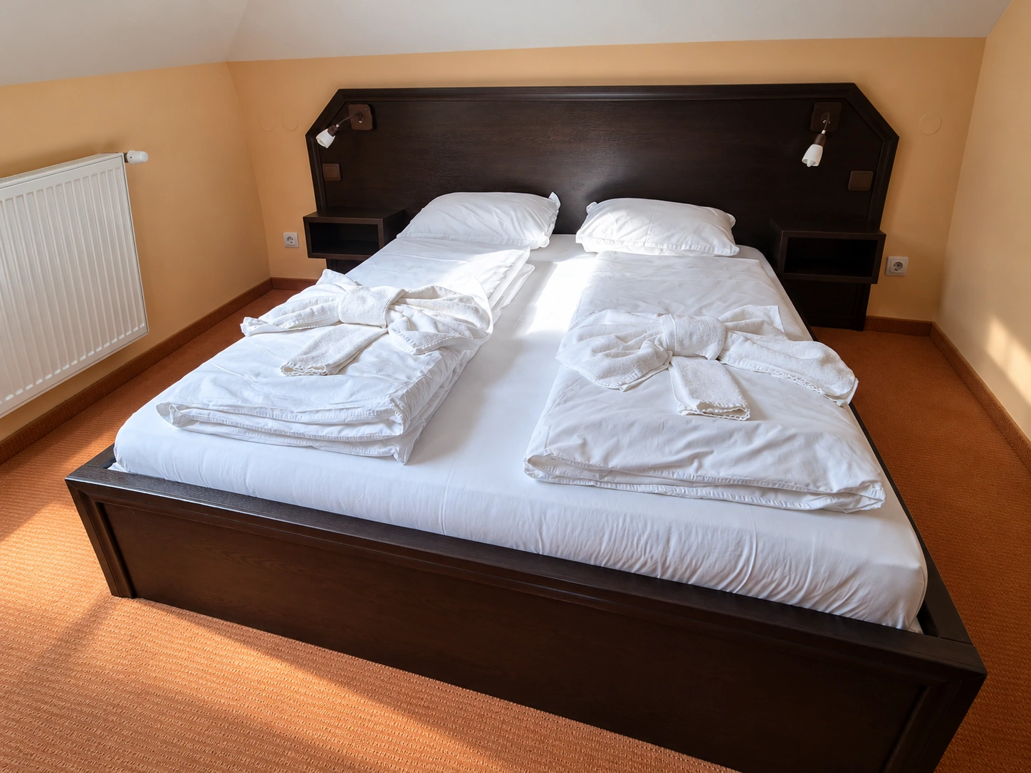 A bedroom under the roof of the Deluxe Apartment, with a large double bed and white linen