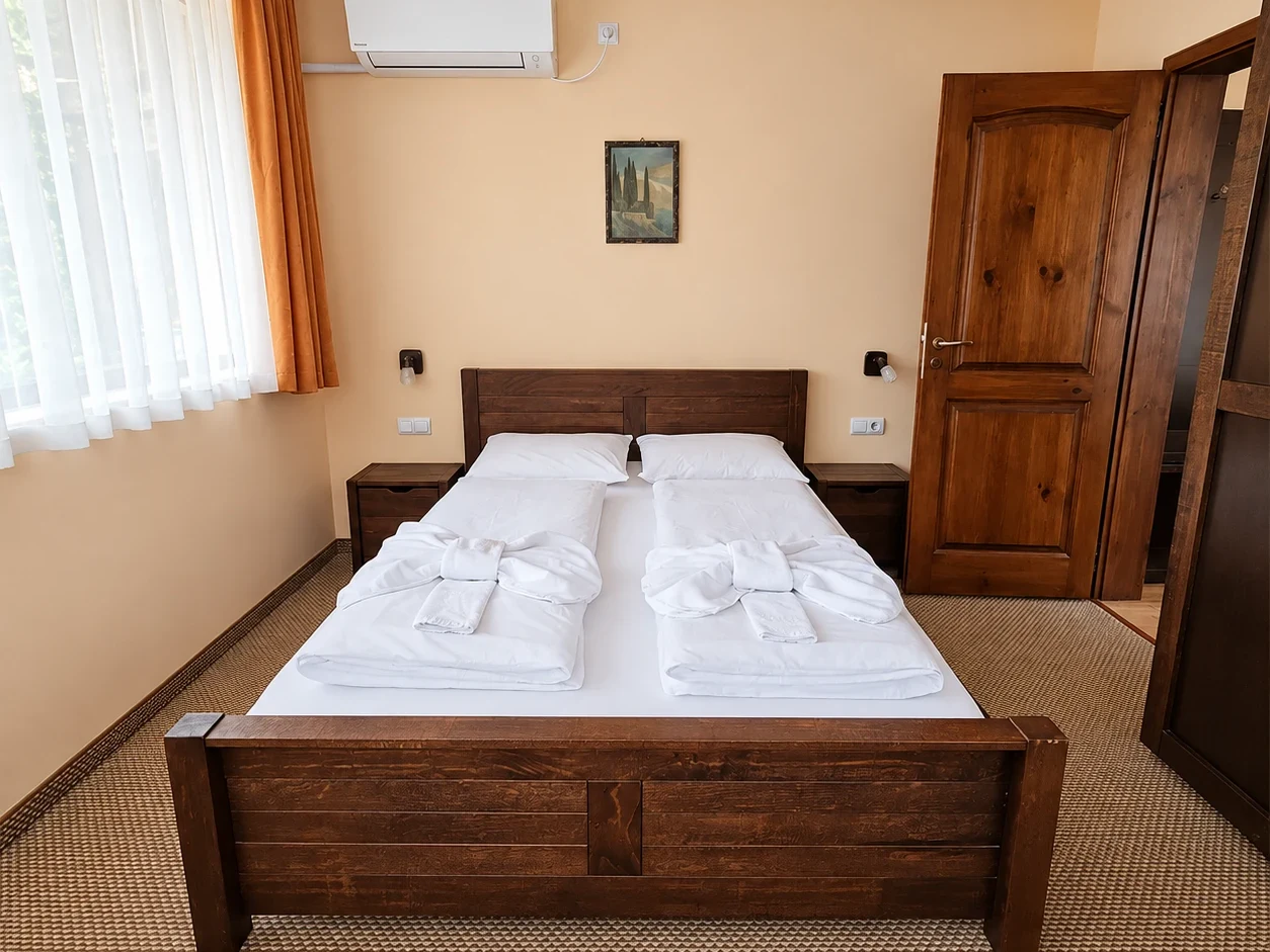 A double bed with a boarded wooden footboard, bedside lamps and a panelled wooden door